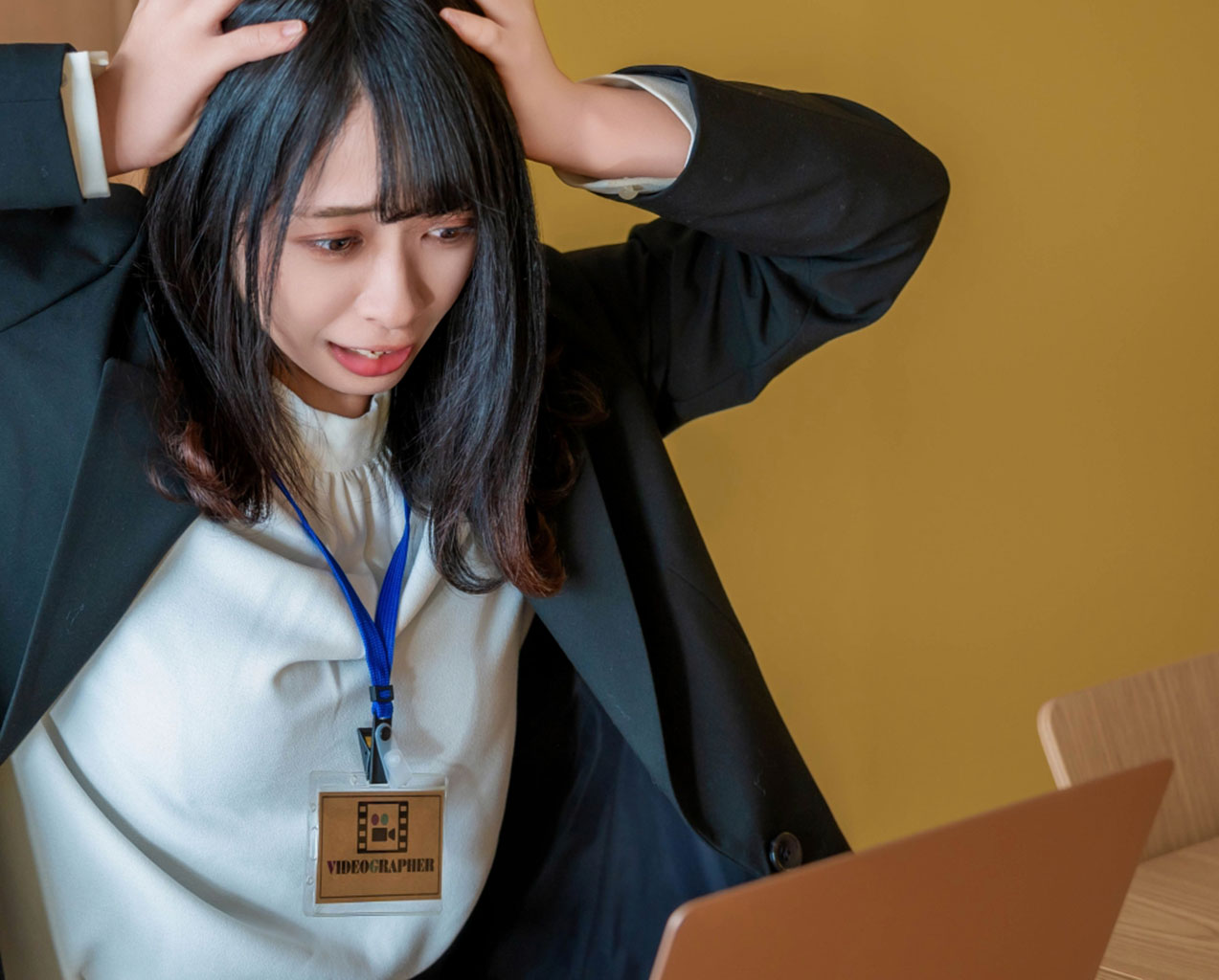 オンライン面接に失敗して頭を抱えるリクルートスーツの女子大学生